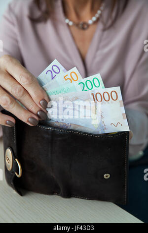 Woman putting couronnes suédoises dans son portefeuille Banque D'Images