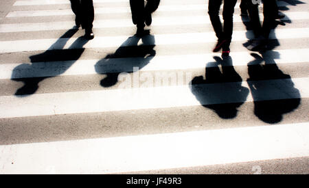 Zebra crossing floue avec les piétons et les ombres des silhouettes Banque D'Images