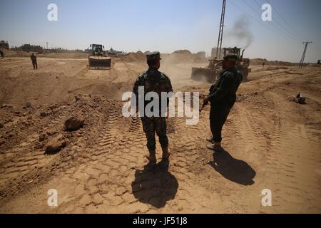 La bande de Gaza. 28 Juin, 2017. Les membres des forces de sécurité palestiniennes se tenir par les bulldozers effacer une zone pour une grande zone tampon à la frontière avec l'Egypte dans le sud de la bande de Gaza ville de Rafah, le 28 juin 2017. Le mouvement islamique Hamas, qui gouverne la bande de Gaza, a commencé à construire une zone de sécurité sur les frontières entre l'enclave côtière et de l'Égypte, un haut responsable du Hamas a déclaré mercredi le responsable de la sécurité. La zone tampon sera de 12 km de long et 100 mètres de large sur la frontière de Gaza, selon une déclaration faite par un agent de sécurité. Credit : Khaled Omar/Xinhua/Alamy Live News Banque D'Images