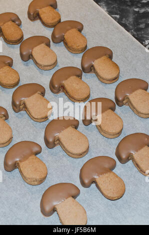 Des biscuits en forme de champignon au chocolat trempée dans le séchage sur un papier cuisson Banque D'Images