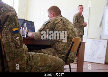 Un officier ukrainien présente sa partie de l'analyse de mission bref au cours de la formation en classe à l'viv centre d'instruction au combat le 30 mai 2017, alors que le personnel de la CCT de l'Ukraine et les mentors affecté à la formation Group-Ukraine multinationales conjointes d'évaluer son rendement. Américains, Britanniques, Polonais, Lituaniens, et des mentors canadiens mènent à la formation du personnel en classe dans le cadre de l'JMTG-U La mission globale de professionnalisation et la construction de la capacité de formation de l'armée ukrainienne. Banque D'Images