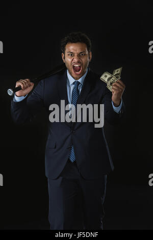 Screaming businessman holding dollar billets et batte de baseball looking at camera Banque D'Images