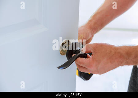 Carpenter l'installation de la serrure sur la porte l'Installation de la serrure de porte. Banque D'Images