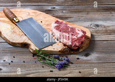 Grand couteau de boucher et le boeuf cru avec sol en matières grasses sur découper avec épices et fines herbes Banque D'Images