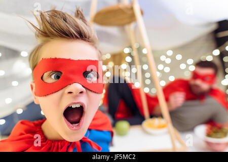 Close-up portrait of boy peu excité en costume de super-héro looking at camera Banque D'Images