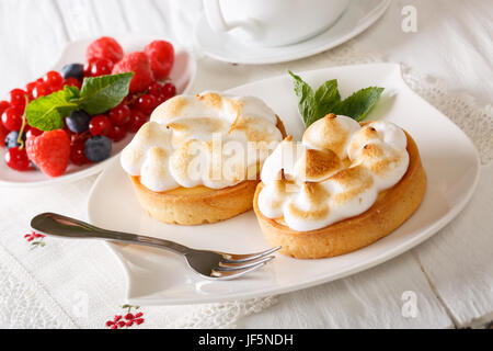 Tartelette citron meringuée avec baies d'été et gros plan sur la table horizontale. Banque D'Images