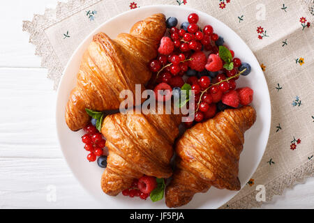 Délicieux croissant au beurre avec les baies fraîches close up sur une plaque horizontale vue du dessus. Banque D'Images