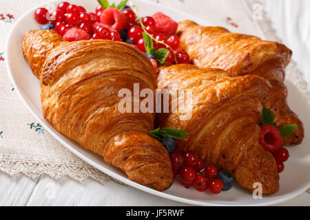 Des croissants frais avec des framboises, myrtilles et groseilles close-up sur une assiette. L'horizontale Banque D'Images