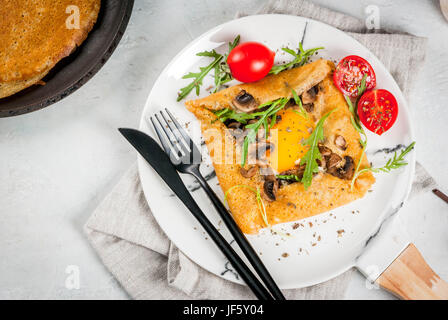 La cuisine française. Le petit-déjeuner, déjeuner et collations. La nourriture végétalienne. Galette au sarrasin plat traditionnel. Crêpes avec œufs, fromage, champignons frits, roquette et Banque D'Images