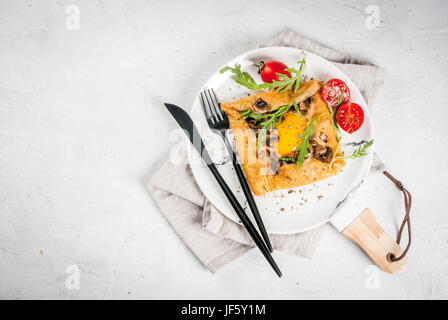 La cuisine française. Le petit-déjeuner, déjeuner et collations. La nourriture végétalienne. Galette au sarrasin plat traditionnel. Crêpes avec œufs, fromage, champignons frits, roquette et Banque D'Images