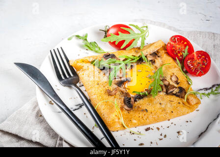 La cuisine française. Le petit-déjeuner, déjeuner et collations. La nourriture végétalienne. Galette au sarrasin plat traditionnel. Crêpes avec œufs, fromage, champignons frits, roquette et Banque D'Images