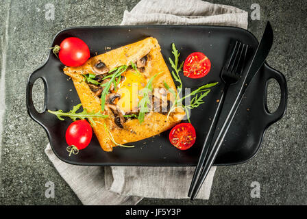 La cuisine française. Le petit-déjeuner, déjeuner et collations. La nourriture végétalienne. Galette au sarrasin plat traditionnel. Crêpes avec œufs, fromage, champignons frits, roquette et Banque D'Images