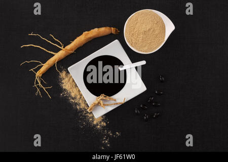 Racine de ginseng, extrait, Poudre et comprimés sur fond noir vue d'en haut. Adaptogène, remède naturel. Banque D'Images