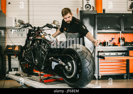 Changement de roue moto mécanicien dans un atelier de réparation de vélo. Mécanicien  moto professionnel travaillant dans le service de réparation de vélo Photo  Stock - Alamy