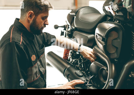 Mécanicien vélo professionnel vérifie le niveau d'huile dans la moto. Sports Le vélo est sur le pont élévateur. Banque D'Images