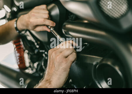 Libre de droit de réparation mécanique moto automobile moto en magasin. L'homme les mains avec des outils spéciaux. Banque D'Images