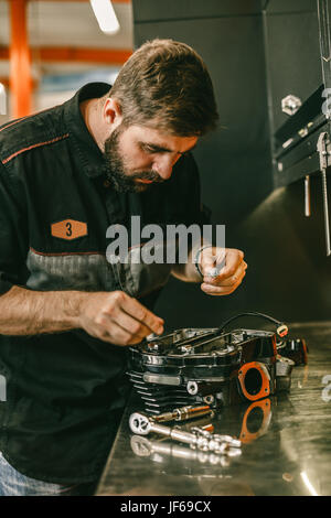 Mécanicien moto Remplacement bougies de préchauffage en vélo moteur. Travaux de remplacement des bougies en atelier de réparation. Banque D'Images