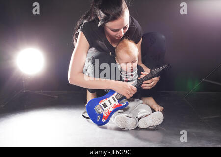 Maman apprend aux jeunes fils jouer de la guitare Banque D'Images