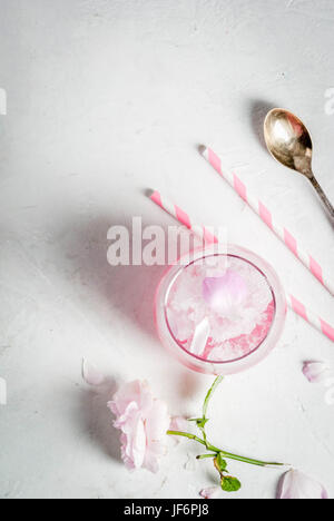 Desserts rafraîchissants de l'été. Régime végétalien, alimentation. Ice cream frozen rose, a gelé, avec des pétales de rose et le vin. Tableau en béton blanc, avec des cuillères, rayé Banque D'Images