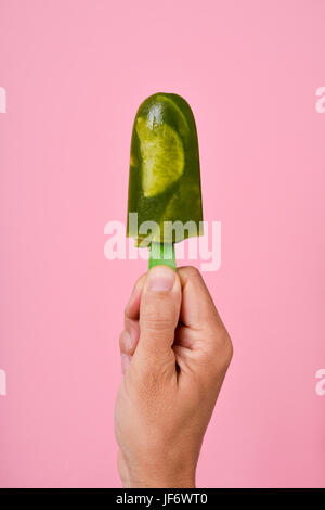 Libre d'un jeune homme de race blanche avec un mojito maison pop de glace dans sa main, contre un fond rose Banque D'Images