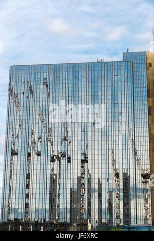 Les grues de construction reflète dans la façade en verre d'un gratte-ciel à Berlin, Allemagne. Banque D'Images