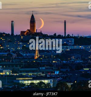 Croissant de lune au-dessus de ville au crépuscule Banque D'Images