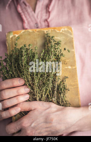 Woman holding vieille recette livre et fines herbes Banque D'Images