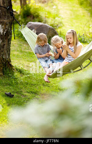 Trois filles assis en hamac tenir les jeunes poulets Banque D'Images