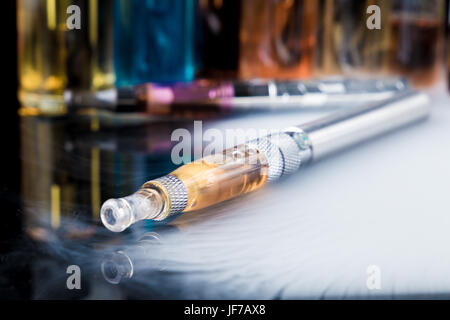 Cigarette électronique e-liquide avec des bouteilles en arrière-plan Banque D'Images