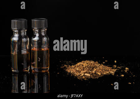 E-liquides à côté de tas de feuilles de tabac broyé Banque D'Images