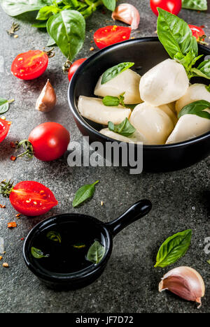 Matières premières agricoles produits biologiques. La cuisson de dîner dans le style italien. Ingrédients pour salade caprese, pâtes, pizza. Le basilic, tomates, fromage mozzarella, olive Banque D'Images