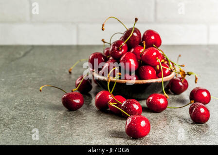 Matières premières fraîches fruits bio de saison. Cerisier avec gouttes d'eau sur une table en pierre. Copy space Banque D'Images