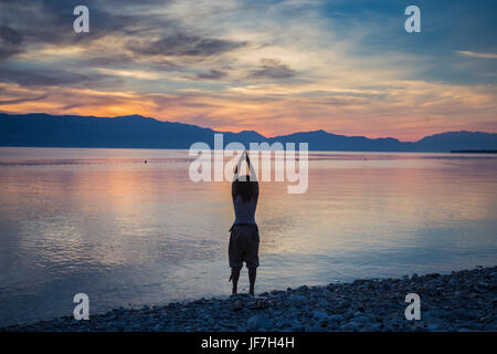 Silhouette d'une femme pratiquant le yoga au lever du soleil Banque D'Images