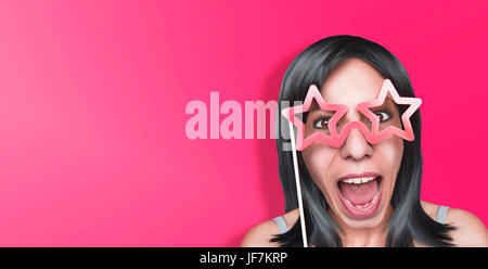 Belle femme gaie avec de faux verres en forme d'Étoile rose, sur fond rose Banque D'Images