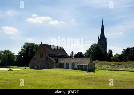 Château d'Oakham, Oakham, Rutland. England UK. L'un des plus beaux exemples d'architecture normande. Il était initialement connu sous le nom de la grande salle et faisait partie d'un ensemble beaucoup plus vaste manoir fortifié. Tous les Saints de l'église paroissiale Oakham peut être vu dans l'arrière-plan. C'est un bel après-midi brumeux avec ciel bleu et très peu de nuages. Banque D'Images