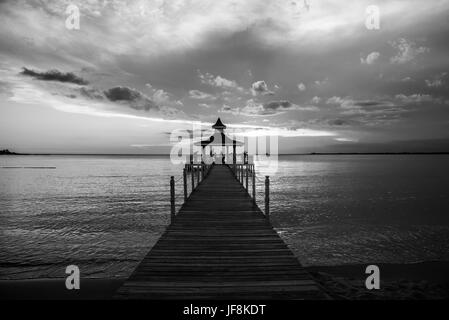 Gazebo bridge au coucher du soleil sur la mer monochrome Banque D'Images