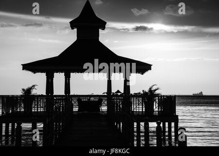 Gazebo bridge au coucher du soleil sur la mer monochrome Banque D'Images