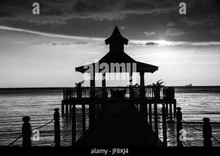 Gazebo bridge au coucher du soleil sur la mer monochrome Banque D'Images