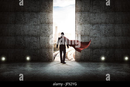 Businessman en costume et cape position à l'encontre d'escalier mur de béton avec des portes énormes ,scène sunrise city skyline vue extérieure . Banque D'Images