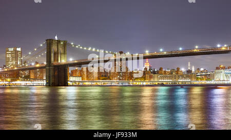 Photo panoramique du pont de Brooklyn avec les lumières de la ville reflète dans la nuit de la rivière East, New York City, USA. Banque D'Images