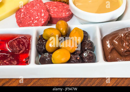 Gros plan du petit-déjeuner turc traditionnel servi dans une assiette de porcelaine d'oliviers, confiture, saucisses, fromage, pâte à tartiner au chocolat et pâte de sésame Banque D'Images