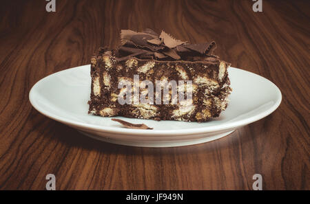 Délicieux gâteau au chocolat et de biscuits mosaïque servi dans une assiette blanche sur une table en bois Banque D'Images