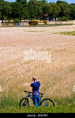 Garching, Allemagne. 30 Juin, 2017. Cycliste s'arrête pour prendre une photo de l'hélicoptère a atterri sur un emplacement pour un appel d'urgence Crédit : Luisa Fumi/Alamy Live News Banque D'Images