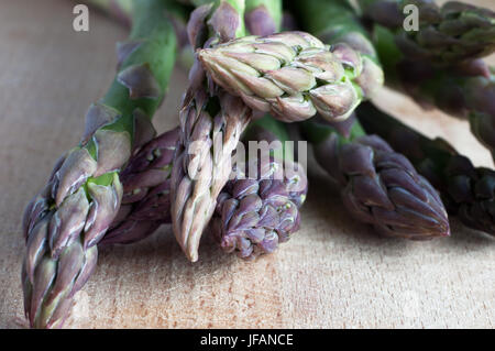 Gros plan (macro) d'un arrangement des asperges (tiges) sur un vieux, rayé, planche à découper en bois. Banque D'Images