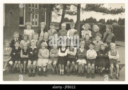 Carte postale représentant une classe d'enfants de l'école avec leur enseignant à l'extérieur posant en uniforme d'été, dans la première rangée est une fille dans étriers, probablement une victime de la polio, vers le début des années 1950, au Royaume-Uni. Banque D'Images