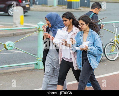 Marcher le long d'amis tout en mangeant et en regardant leurs smartphones. Banque D'Images
