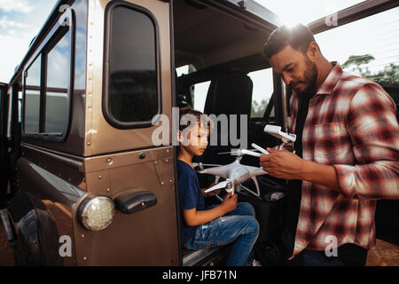 Shot de père et fils à l'arrière de leur voiture mise en place d'un drone pour voler. Jeune homme et fils de l'assemblage d'un drone on road trip. Banque D'Images