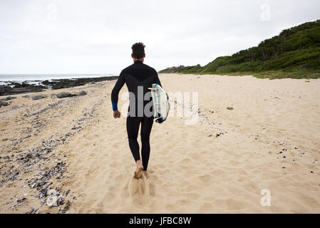 Surfer promenades le long beach Banque D'Images