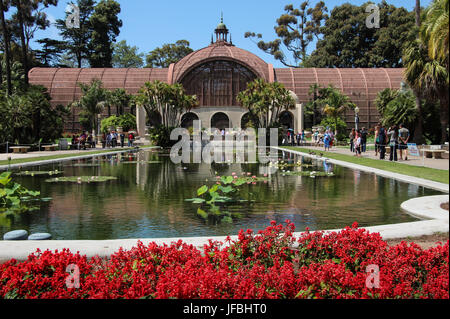 L'une des plus grandes structures, la latte construit Bâtiment botanique dans Balboa Park, San Diego, vue sur l'étang aux nénuphars, les fleurs rouges, ciel bleu Banque D'Images