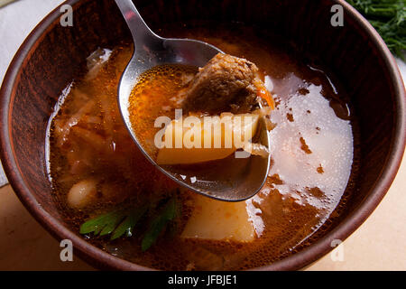 Vue rapprochée de la plaque d'argile et une cuillère à soupe de betteraves rouges ou borsch. Le bortsch ukrainien soupe à la tomate sur fond de bois. Banque D'Images